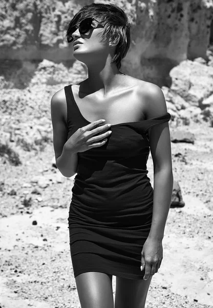 Moda elegante bella giovane modello di donna bruna in estate vestito blu posa vicino rocce di sabbia — Foto Stock