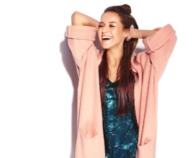 Güzel gülümseyen hipster esmer kadın modeli şık pembe palto ve beyaz arka plan üzerinde izole mavi gece elbisesi