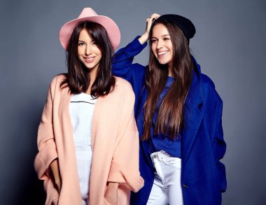 iki esmer bayan modelleri yaz casual hipster palto gri arka plan üzerinde poz içinde gülümseyen moda portre