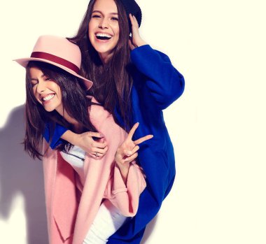 iki esmer bayan modelleri yaz casual hipster palto üzerine beyaz izole içinde gülümseyen moda portre. Birbirlerine arkasında tutarak kızlar 