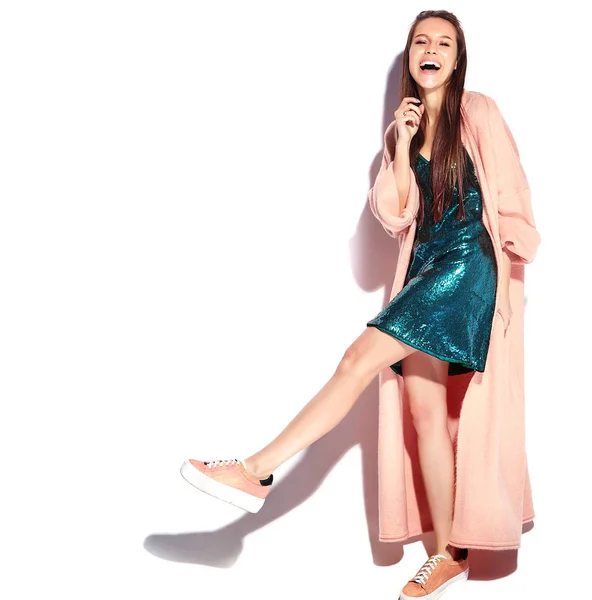 Belle modèle de femme brune hipster souriante en manteau rose élégant et robe de soirée bleue isolée sur fond blanc — Photo
