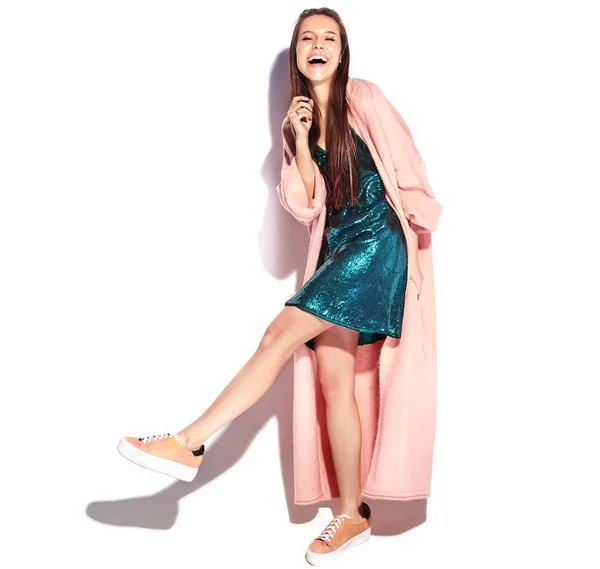 Bonito modelo de mulher morena hipster sorridente em casaco rosa elegante e vestido de noite azul isolado no fundo branco — Fotografia de Stock