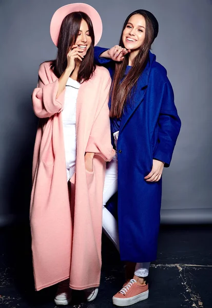 Modeporträt von zwei lächelnden brünetten Models im sommerlichen lässigen Hipster-Mantel, die auf grauem Hintergrund posieren — Stockfoto