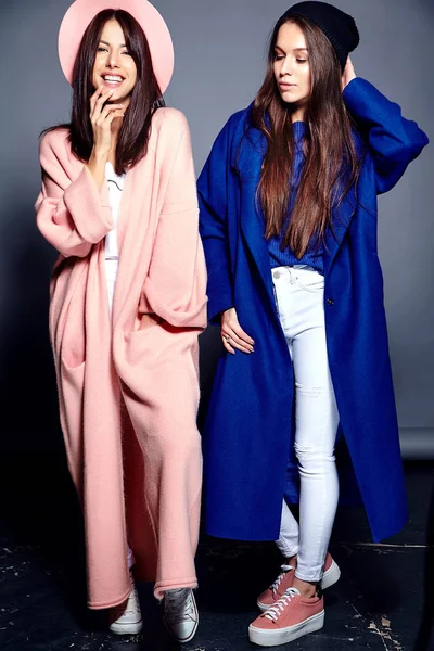 Retrato de moda de dos mujeres morenas sonrientes modelos en verano abrigo hipster casual posando sobre fondo gris —  Fotos de Stock