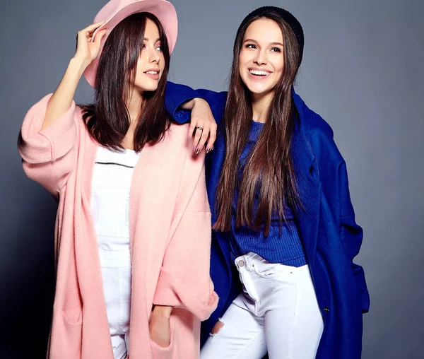 Retrato de moda de dos mujeres morenas sonrientes modelos en verano abrigo hipster casual posando sobre fondo gris —  Fotos de Stock