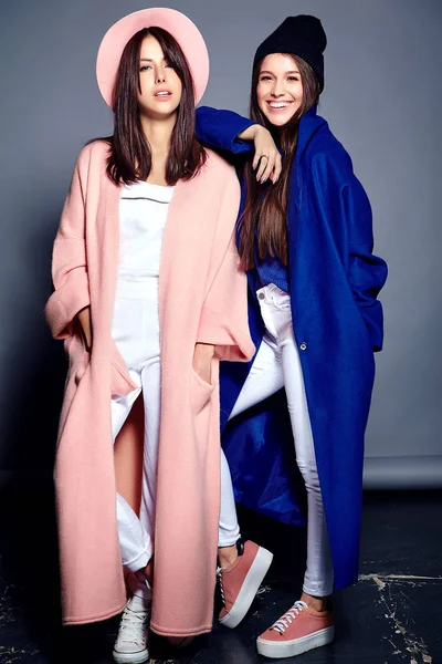 Retrato de moda de dos mujeres morenas sonrientes modelos en verano abrigo hipster casual posando sobre fondo gris —  Fotos de Stock