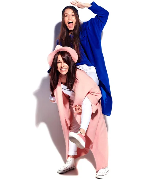 Retrato de moda de dos mujeres morenas sonrientes modelos en abrigo hipster casual de verano aislado en blanco. Chicas abrazándose en la espalda —  Fotos de Stock
