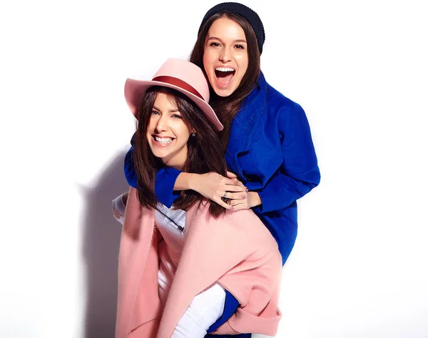 Retrato de moda de dos mujeres morenas sonrientes modelos en abrigo hipster casual de verano aislado en blanco. Chicas abrazándose en la espalda —  Fotos de Stock