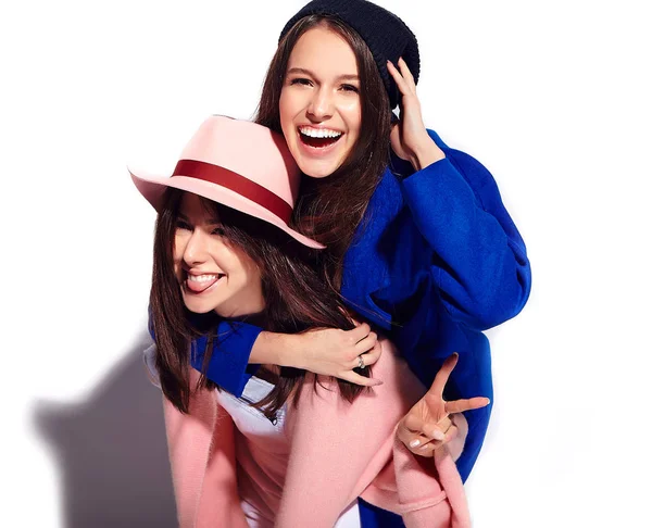 Potret mode dari dua model wanita berambut coklat tersenyum di musim panas mantel hipster biasa terisolasi di atas putih. Gadis memegang satu sama lain di belakang — Stok Foto