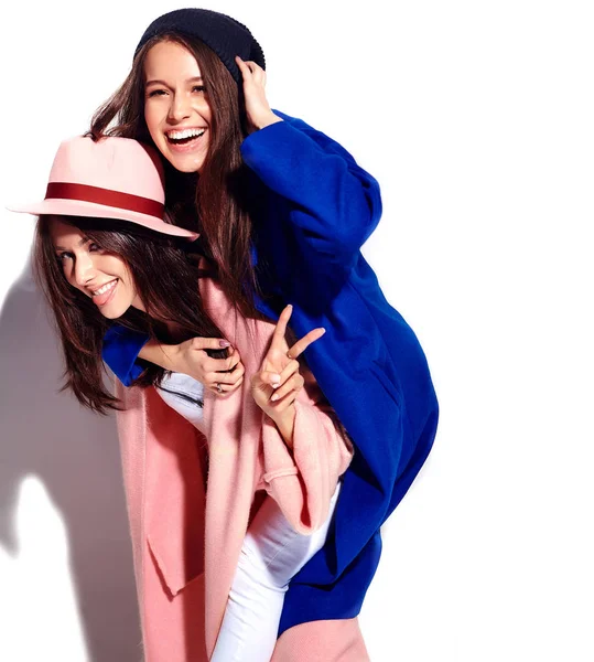 Fashion portrait of two smiling brunette women models in summer casual hipster overcoat isolated on white. Girls holding each other on back — Stock Photo, Image