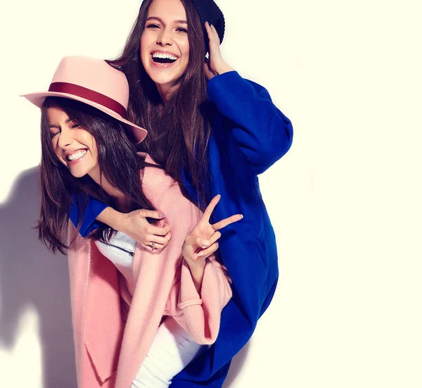 Retrato de moda de dos mujeres morenas sonrientes modelos en abrigo hipster casual de verano aislado en blanco. Chicas abrazándose en la espalda — Foto de Stock