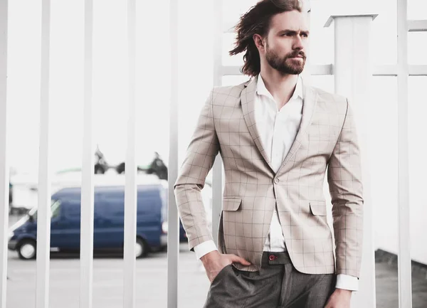 Portrait of sexy handsome fashion male model man dressed in elegant checkered suit posing outdoors on the street background — Stock Photo, Image