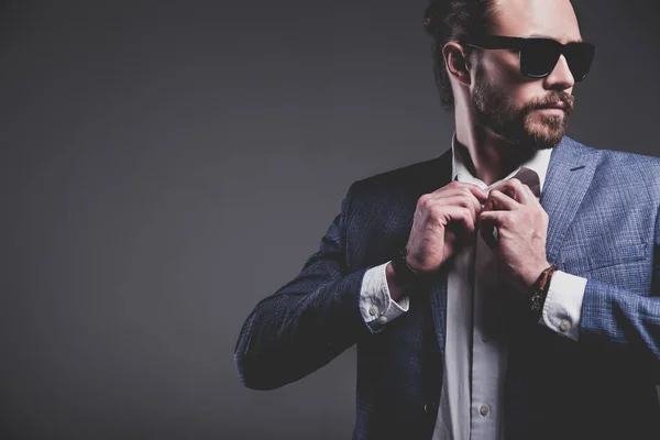 Guapo moda elegante hipster hombre de negocios modelo vestido con elegante traje azul posando sobre fondo gris —  Fotos de Stock