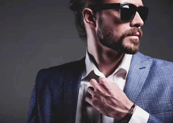 Bello moda elegante hipster modello uomo d'affari vestito in elegante abito blu in posa su sfondo grigio — Foto Stock
