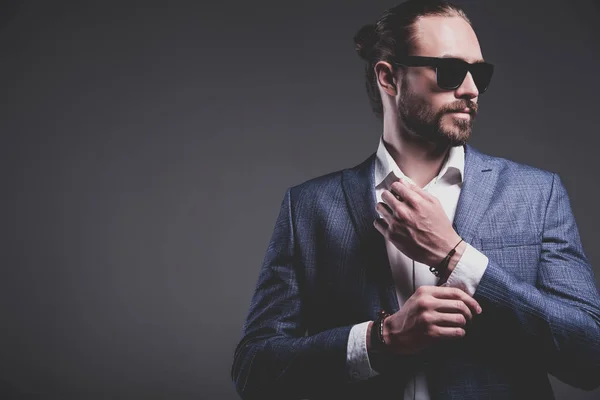 Guapo moda elegante hipster hombre de negocios modelo vestido con elegante traje azul posando sobre fondo gris —  Fotos de Stock