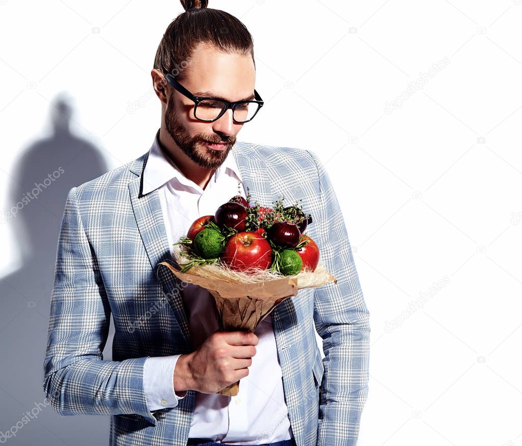 portrait of handsome fashion stylish hipster businessman model man dressed in elegant light blue suit in glasses isolated on white with fresh bouquet of creative flowers
