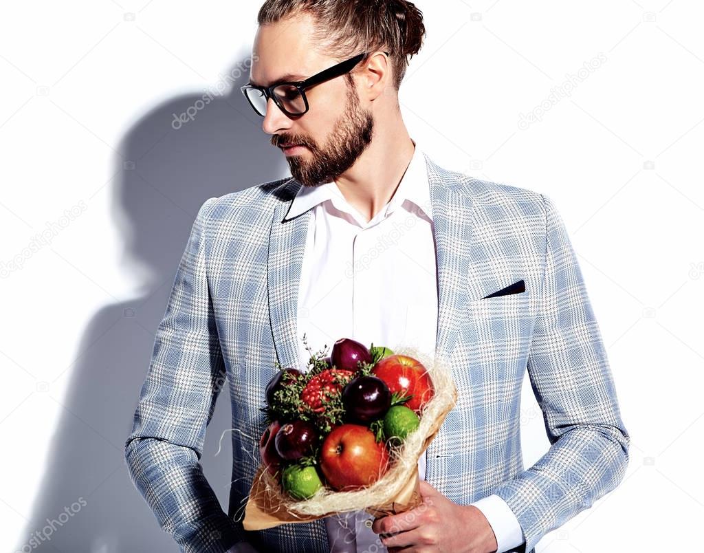 portrait of handsome fashion stylish hipster businessman model man dressed in elegant light blue suit in glasses isolated on white with fresh bouquet of creative flowers