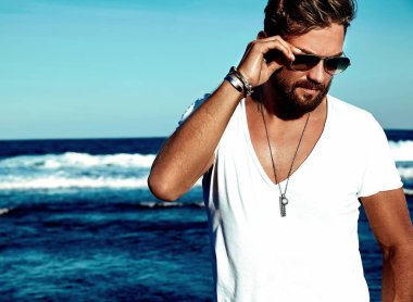 Mavi deniz arka plan üzerinde poz portre yakışıklı moda giyen adam model beyaz elbise