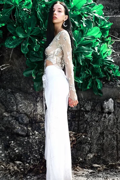 ワイド脚クラシック パンツ熱帯のエキゾチックな緑の背景に近いポーズで長い黒髪の美しい白人女性モデルのポートレート — ストック写真