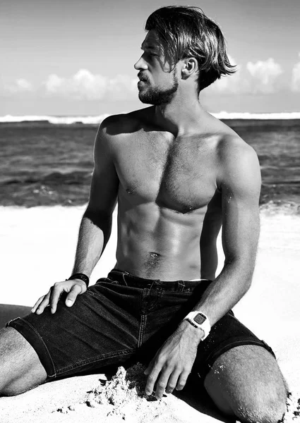 Портрет красивої сонячної моделі чоловіка, що позує на літньому пляжі з білим піском на блакитному небі та океанічному фоні — стокове фото