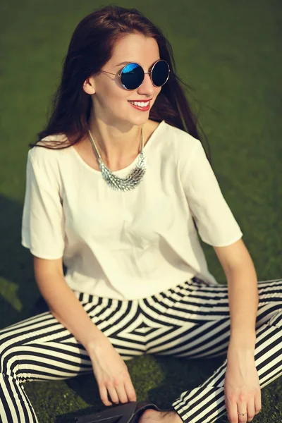 Moda elegante bela jovem morena modelo de mulher no verão hipster roupas casuais posando no fundo da rua no parque — Fotografia de Stock