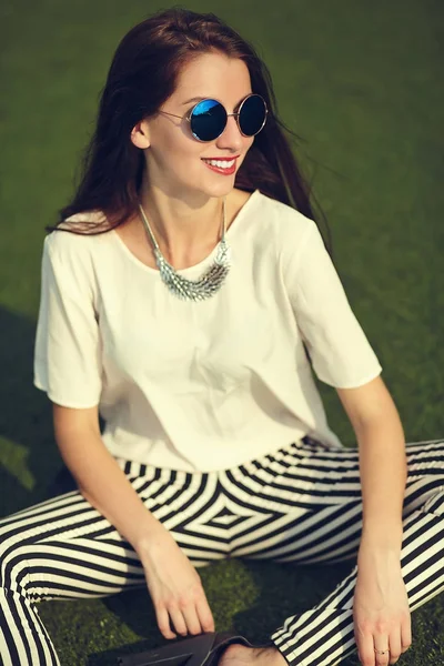 Stijlvolle mooie jonge brunette vrouw mannequin in zomer hipster casual kleding poseren op straat achtergrond in het park — Stockfoto