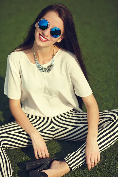 Stijlvolle mooie jonge brunette vrouw mannequin in zomer hipster casual kleding poseren op straat achtergrond in het park — Stockfoto