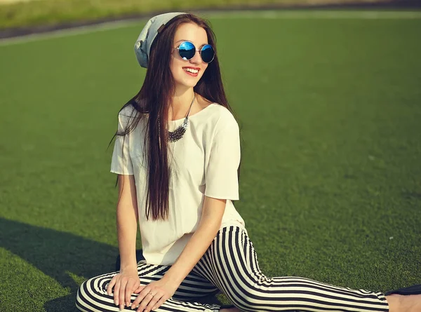 Stijlvolle mooie jonge brunette vrouw mannequin in zomer hipster casual kleding poseren op straat achtergrond in het park — Stockfoto