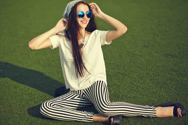 Snygg vacker ung brunett kvinna modell i sommar hipster casual kläder poserar på gatan bakgrund i parken — Stockfoto