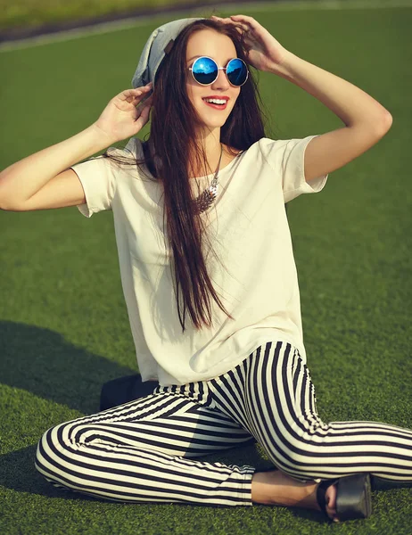 Moda elegante bella giovane bruna modello donna in estate hipster vestiti casual in posa su sfondo strada nel parco — Foto Stock