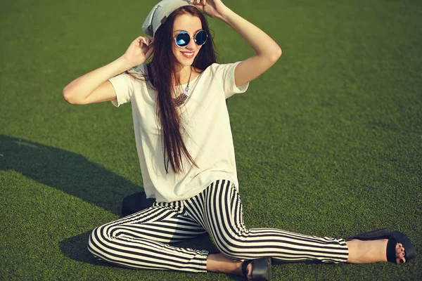 Snygg vacker ung brunett kvinna modell i sommar hipster casual kläder poserar på gatan bakgrund i parken — Stockfoto