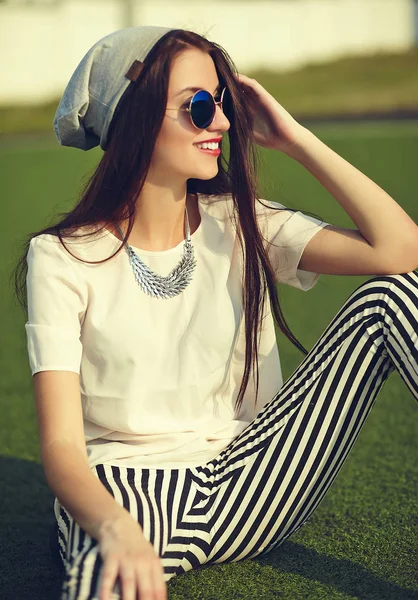 Stijlvolle mooie jonge brunette vrouw mannequin in zomer hipster casual kleding poseren op straat achtergrond in het park — Stockfoto
