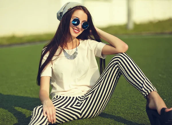 Stijlvolle mooie jonge brunette vrouw mannequin in zomer hipster casual kleding poseren op straat achtergrond in het park — Stockfoto