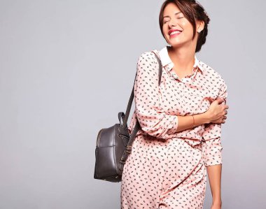 Güzel gülümseyen şirin esmer kadın modeli rahat yaz giysileri handback ile gri arka plan üzerinde izole hiç makyaj ile portresi