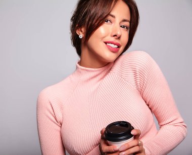 Güzel gülümseyen şirin esmer kadın model gri izole hiç makyaj ile rahat yaz pembe giysileri portresi. Kahve içme