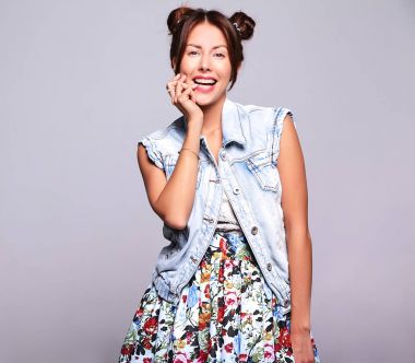 Güzel gülümseyen şirin esmer kadın model gri izole boynuzları saç modeli ile hiç makyaj ile rahat yaz kot pantolon giysili portresi. Parmağını ısırma