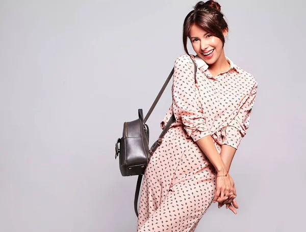 Güzel gülümseyen şirin esmer kadın modeli rahat yaz giysileri handback ile gri arka plan üzerinde izole hiç makyaj ile portresi