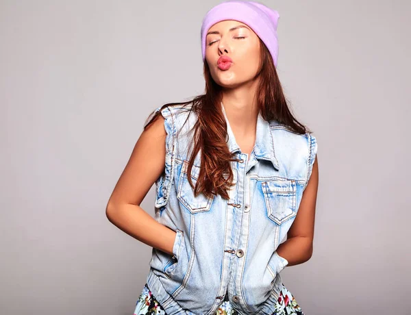 Portre rahat yaz kot giysileri güzel şirin esmer kadın modeli gri izole mor beanie hiç makyaj ile. Hava öpücük vererek