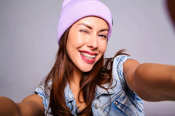 Mor beanie smartphone üzerinde gri izole selfie fotoğraf yapma hiç makyaj ile rahat yaz kot giysileri güzel şirin esmer kadın modeli portresi