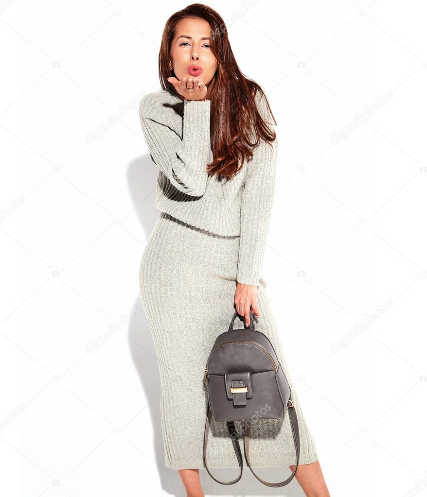 Portrait of beautiful cute brunette woman model in casual autumn gray sweater clothes with no makeup isolated on white with handbag. GIving a kiss