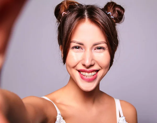グレーに分離されたスマート フォンで Selfie 写真を作る化粧品のカジュアルな服でかわいいブルネット美人モデルの肖像 — ストック写真