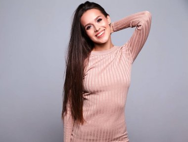 Güzel şirin esmer kadın modeli rahat sıcak bej kazaklı portresi izole üzerinde gri elbise