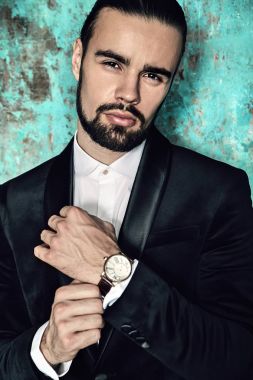 yakışıklı moda şık hipster lumbersexual işadamı modelinin portre Studio mavi grange duvarının yakınında poz içinde zarif siyah takım elbise giymiş. Metroseksüel