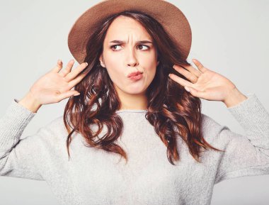 Genç şık gülen kız modeli gri rahat yaz giysileri ile doğal makyaj gri arka plan üzerinde izole kahverengi şapkalı portresi. Kameraya bakarak