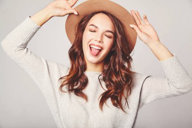 Genç şık gülen kız modeli gri rahat yaz giysileri ile doğal makyaj gri arka plan üzerinde izole kahverengi şapkalı portresi. Kameraya bakarak