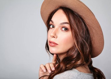 Genç şık kız modeli gri rahat yaz giysileri ile doğal makyaj gri arka plan üzerinde izole kahverengi şapkalı portresi. Kameraya bakarak