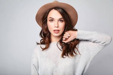 Genç şık gülen kız modeli gri rahat yaz giysileri ile doğal makyaj gri arka plan üzerinde izole kahverengi şapkalı portresi. Kameraya bakarak