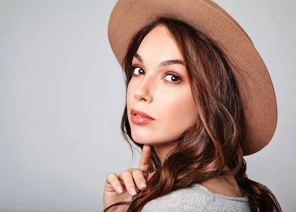 Genç şık kız modeli gri rahat yaz giysileri ile doğal makyaj gri arka plan üzerinde izole kahverengi şapkalı portresi. Kameraya bakarak