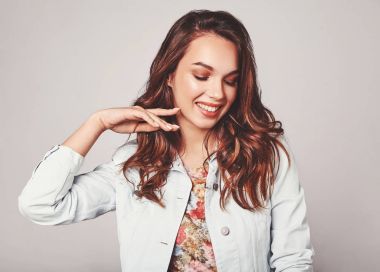Genç şık gülen kız modeli renkli rahat yaz giysileri ile doğal makyaj gri arka plan üzerinde izole portresi. Kameraya bakarak