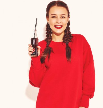 Mutlu gülümseyen kadın model parlak makyaj ve renkli dudakları ile iki boynuzu ve güneş gözlüğü üzerinde beyaz izole kırmızı yaz giysileri ile. Saman ile cam şişe soda içme
